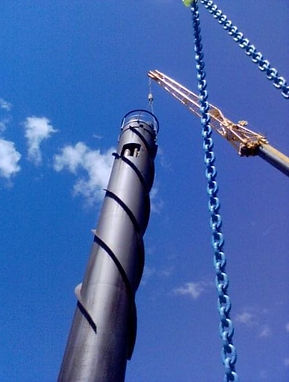 Kranbil lyfter upp verktyg på torn.